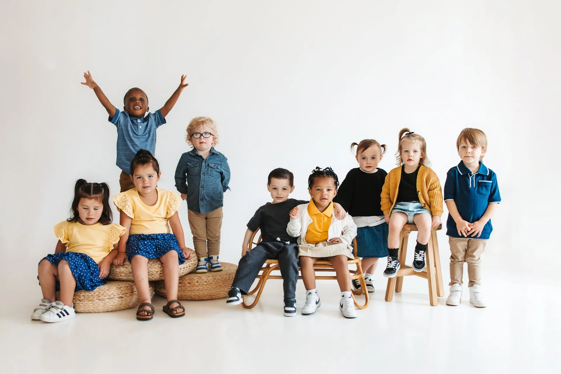 A joyful group of preschool and elementary children gathered together in a bright, sunlit studio