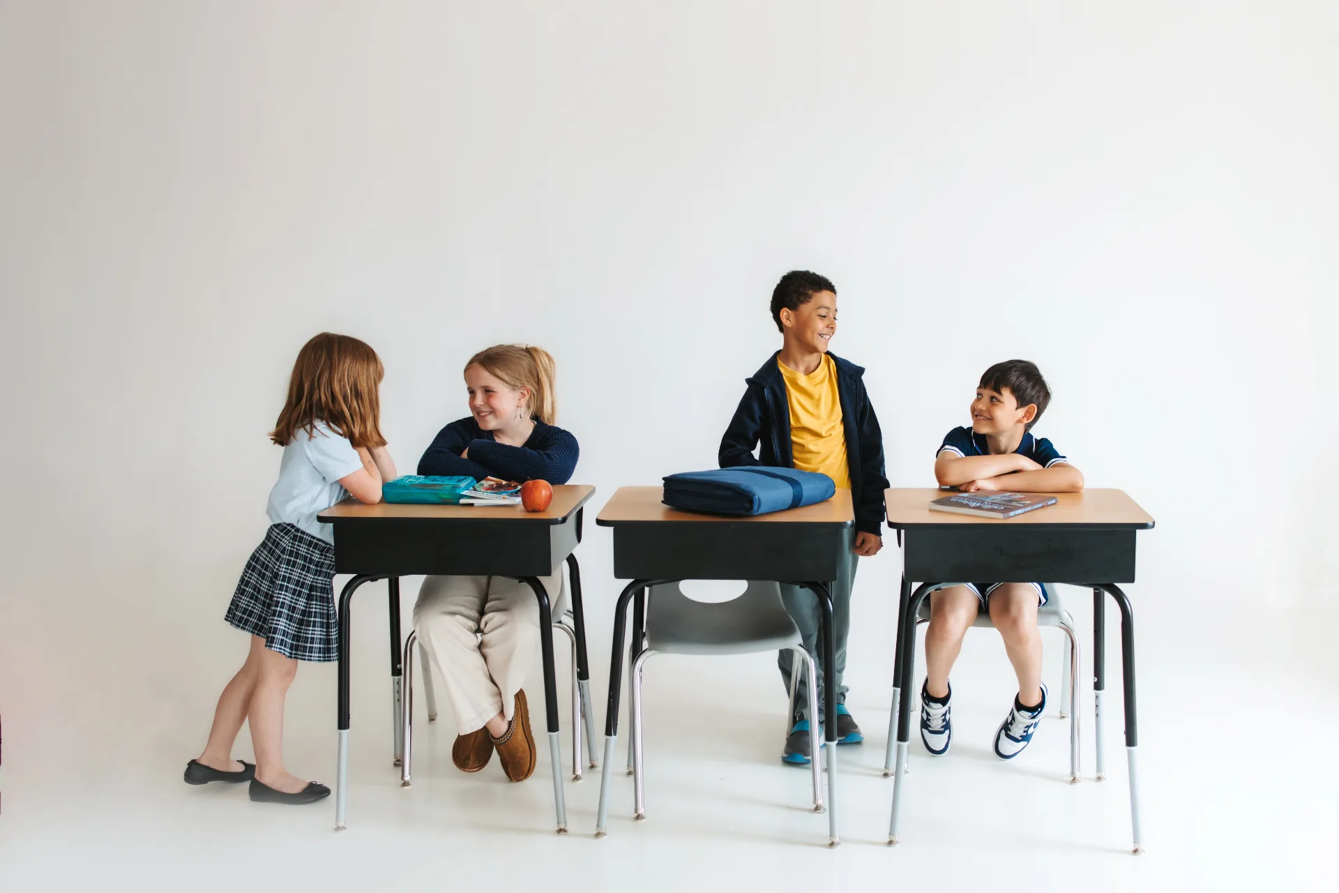 Four Way Christian Academy elementary students smiling and chatting at their desks in a bright, modern classroom